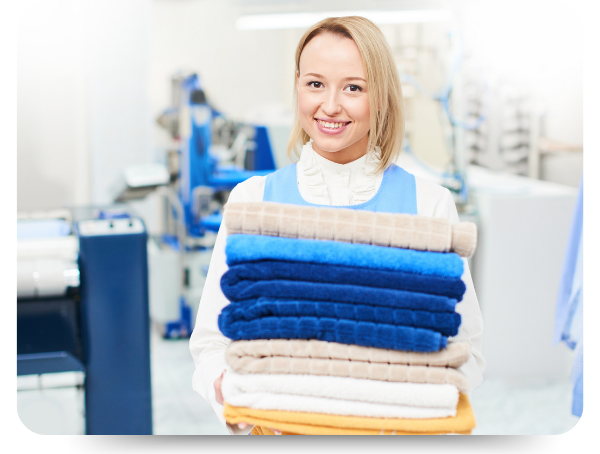 dry cleaning employee holding a stack of folded towels